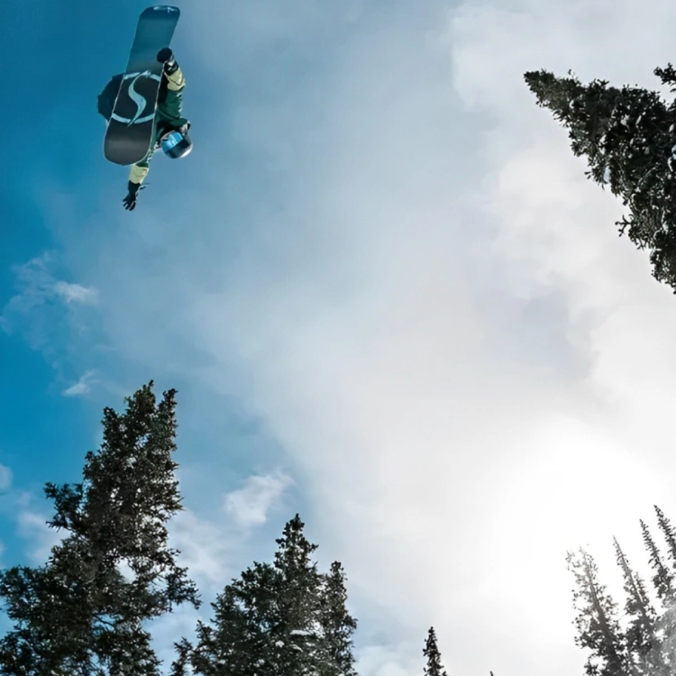 Snowboarder backflip, sunny winter sky.